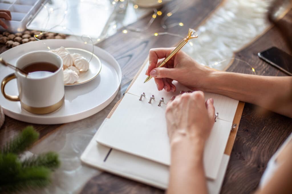 woman's hands writing in a journal